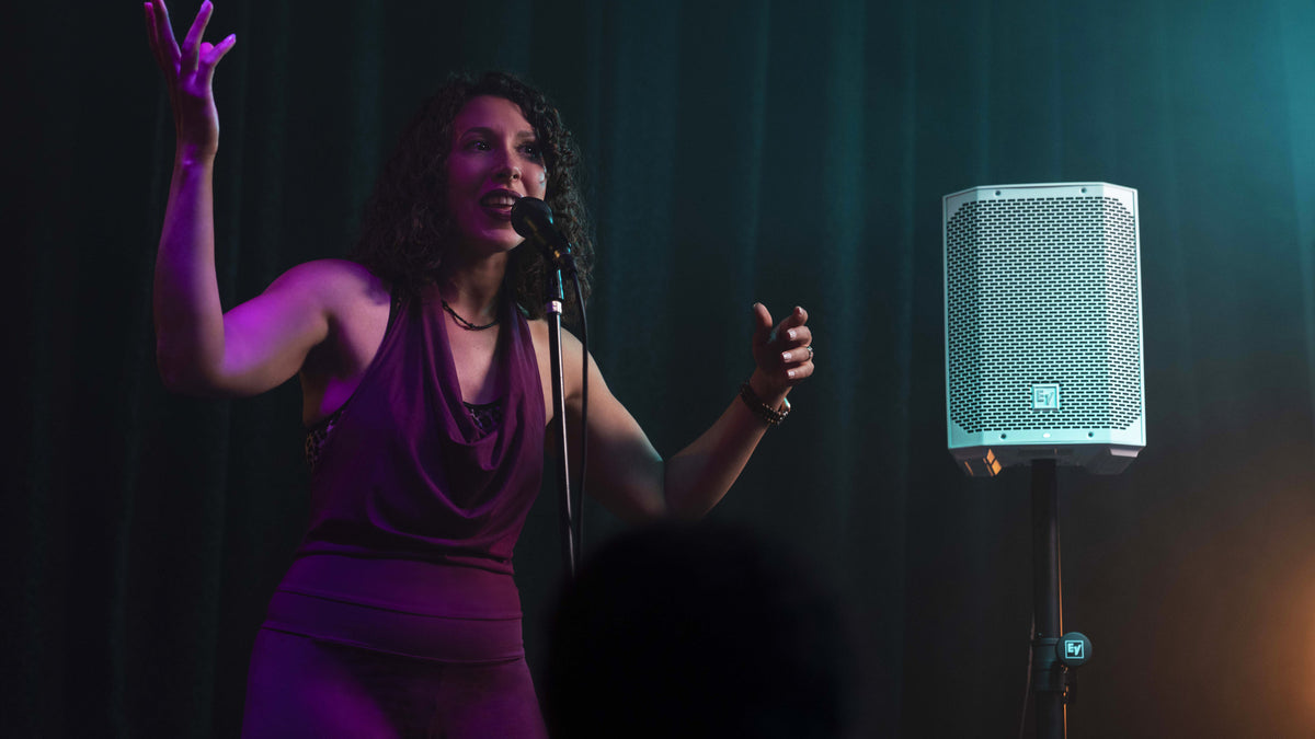 A singer performing on stage beside an Electro-Voice Everse 8 speaker