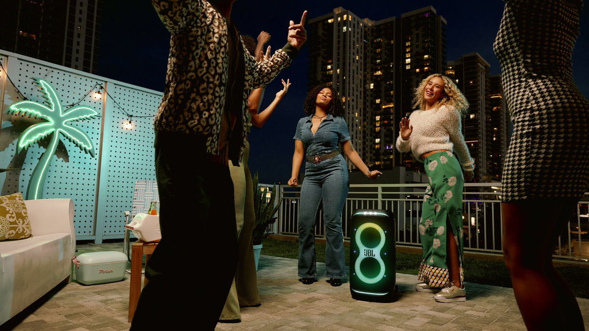Friends dancing on a rooftop at night with a JBL PartyBox Stage 320